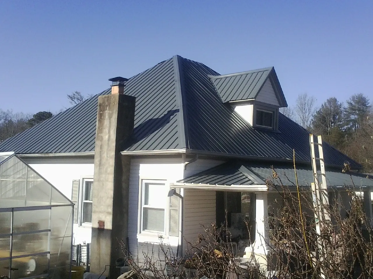 Dark blue standing seam metal roof on a white farmhouse with dormer — Slate & Tile Roof Repair by Roofing Brothers in Pomfret