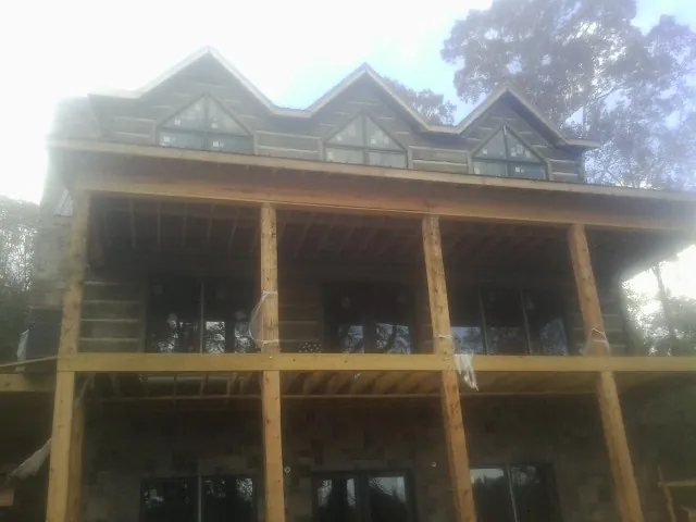 Dormers and porch framing on a large log home under construction — Roof Coating work by our crew in Pomfret