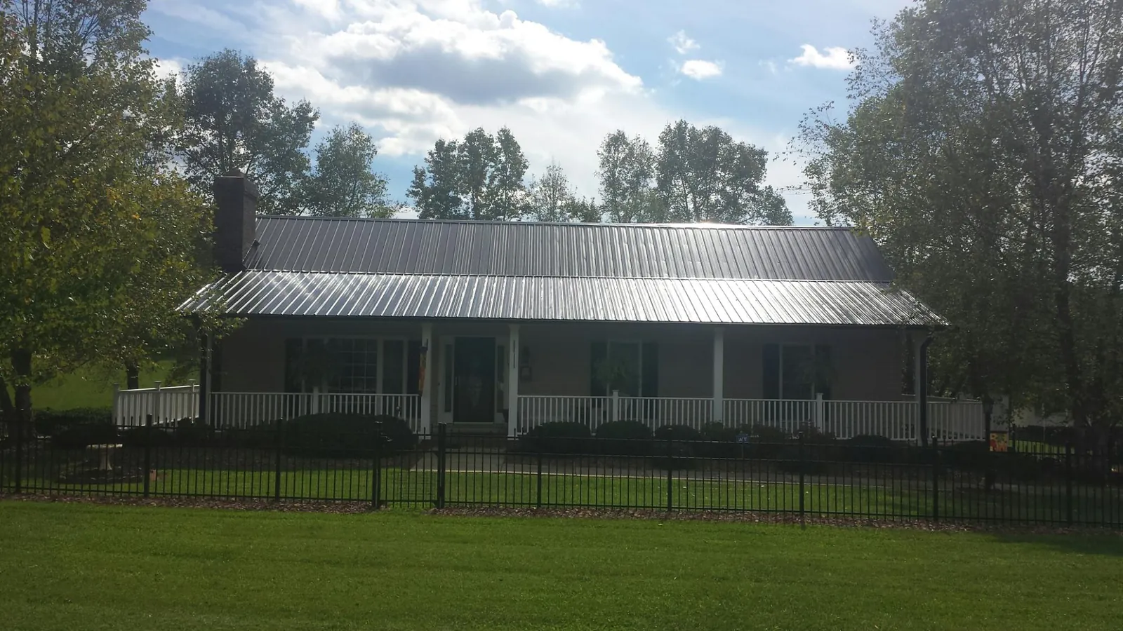 Gray metal roof on a brick ranch with a full width front porch — Gutter Guard Installation work by our crew in Pomfret