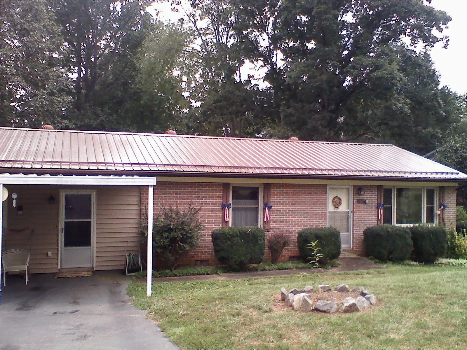 Bronze metal roof and carport on a brick ranch home — Roof Repair work by our crew in Pomfret